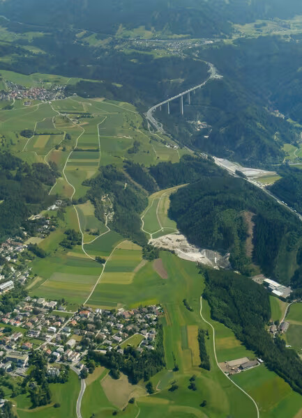 Hände halten dunkle Ackererde mit Saatgut über einem Feld